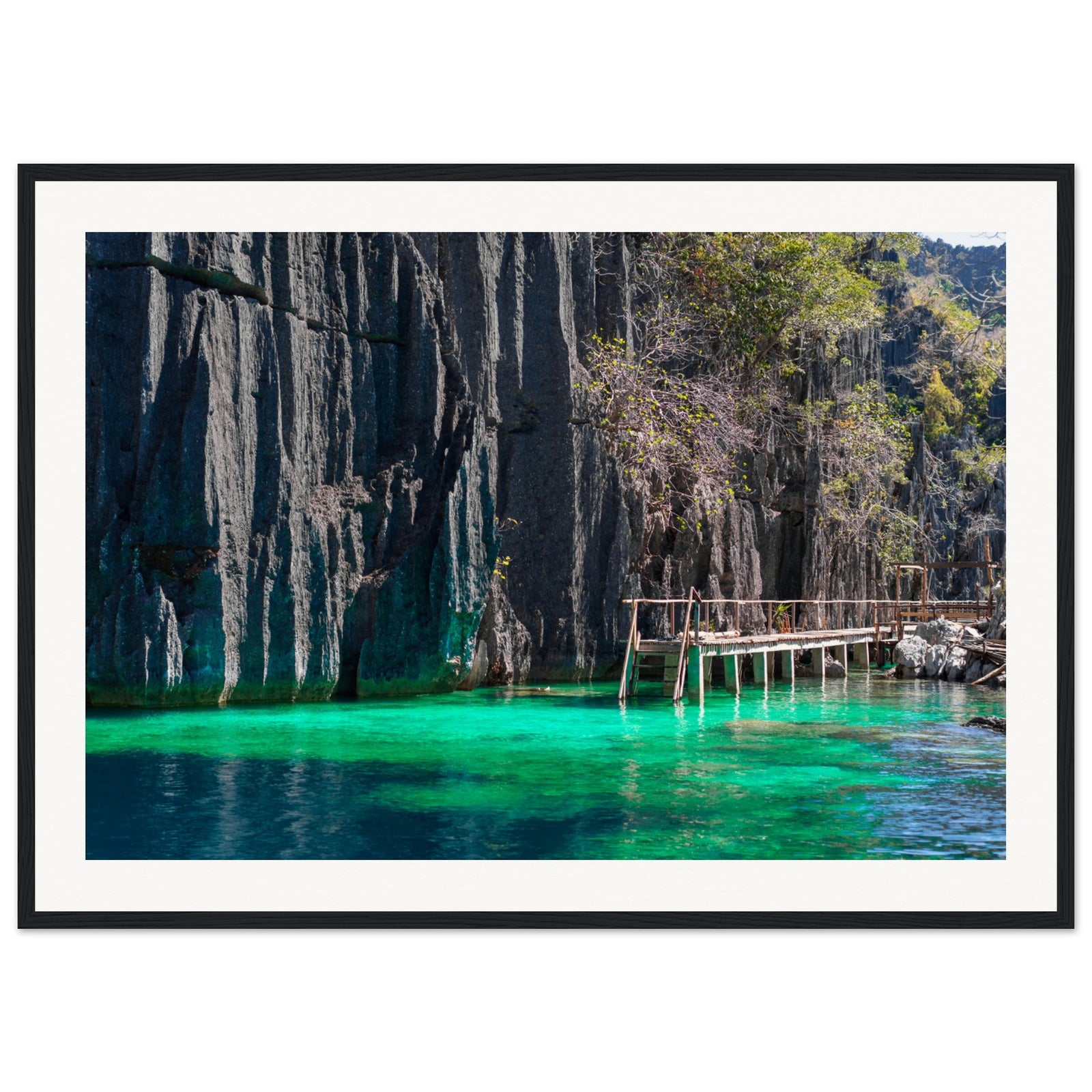 Framed tropical retreat scene with bright water and stone cliffs.