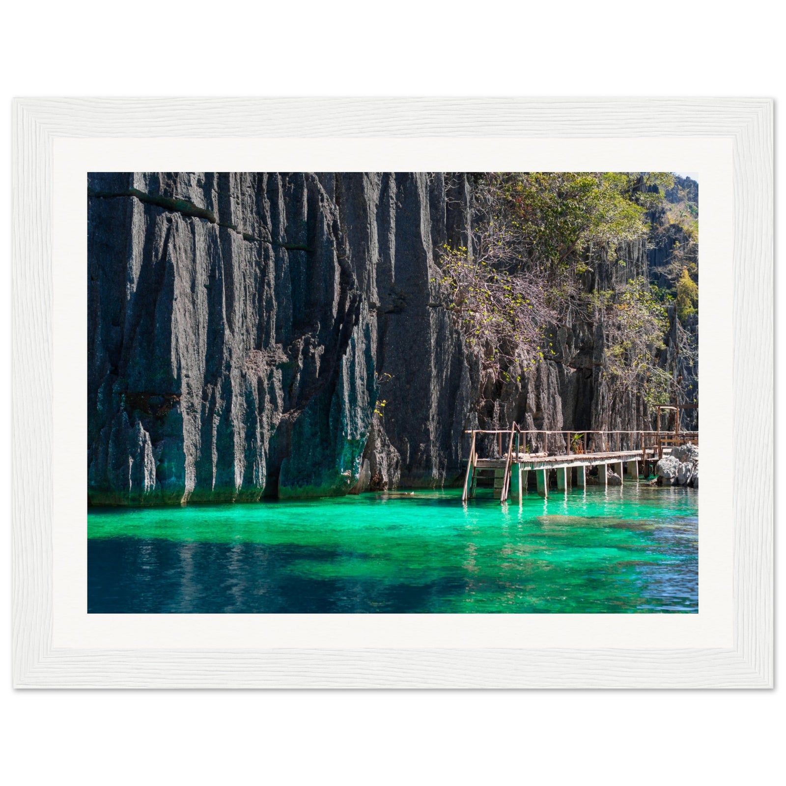 Framed landscape of turquoise waters and vertical rock walls with vegetation.