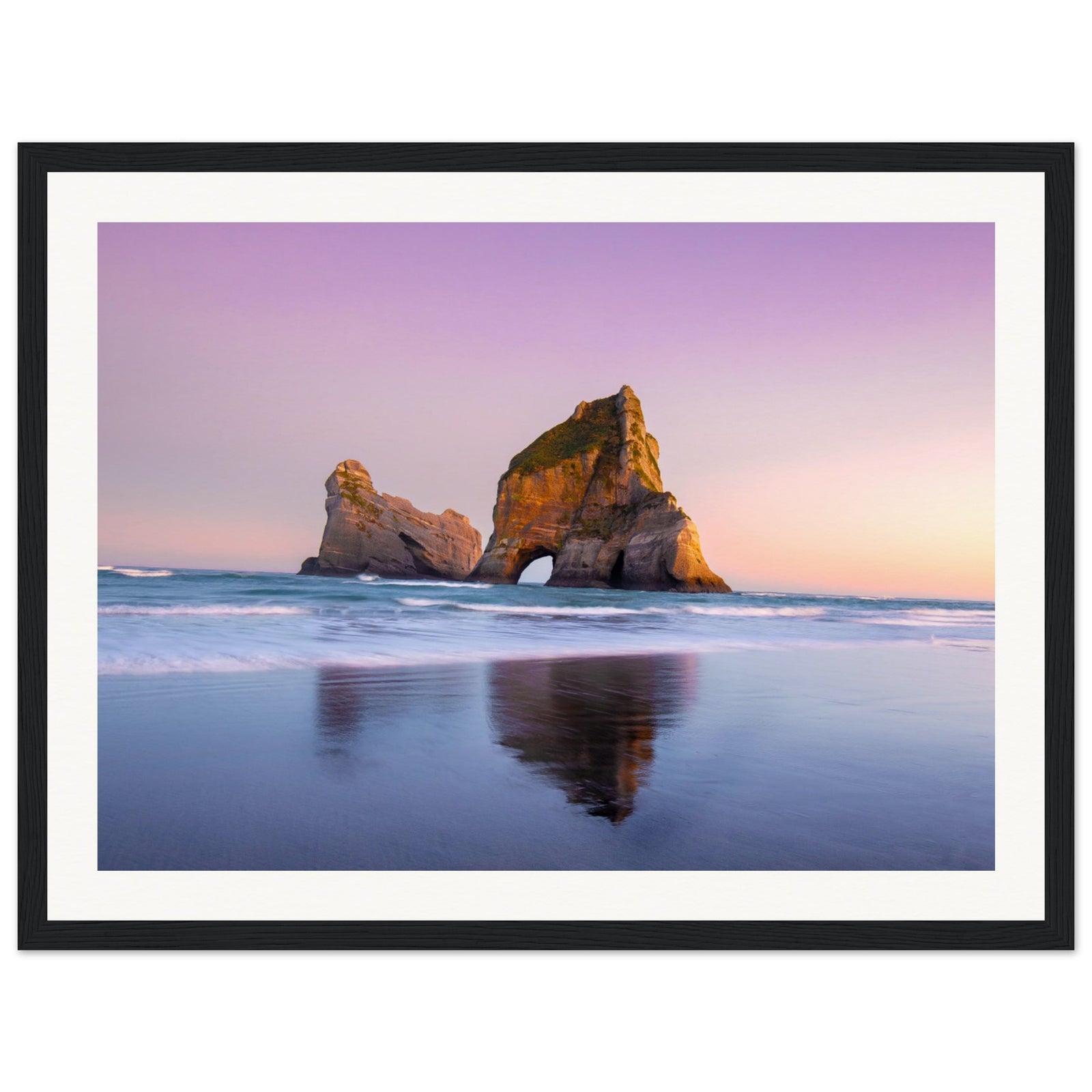Portrait of tranquil beach waves and towering sea rock.