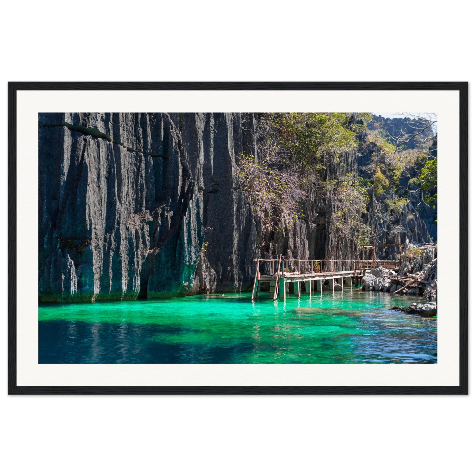 Vivid green water along dark rock cliffs in a portrait photograph.