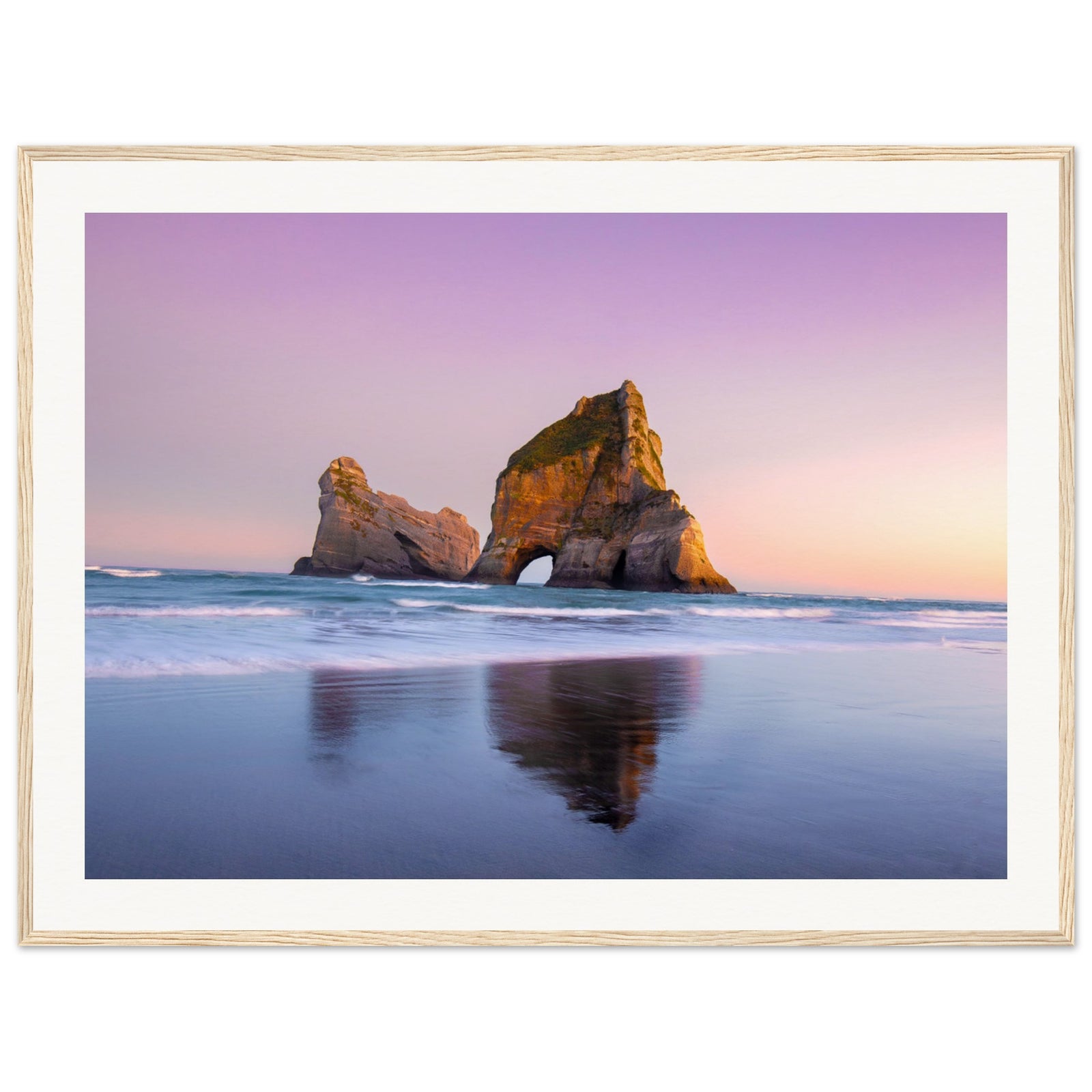 Framed ocean view of rock arch during calm sunset.