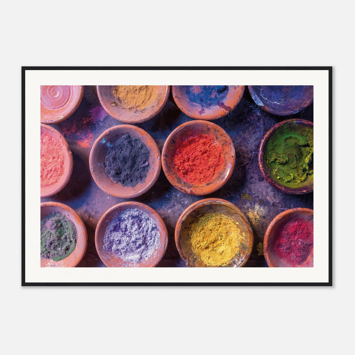 Framed top-down view of vibrant pigment bowls in earthy dishes.


