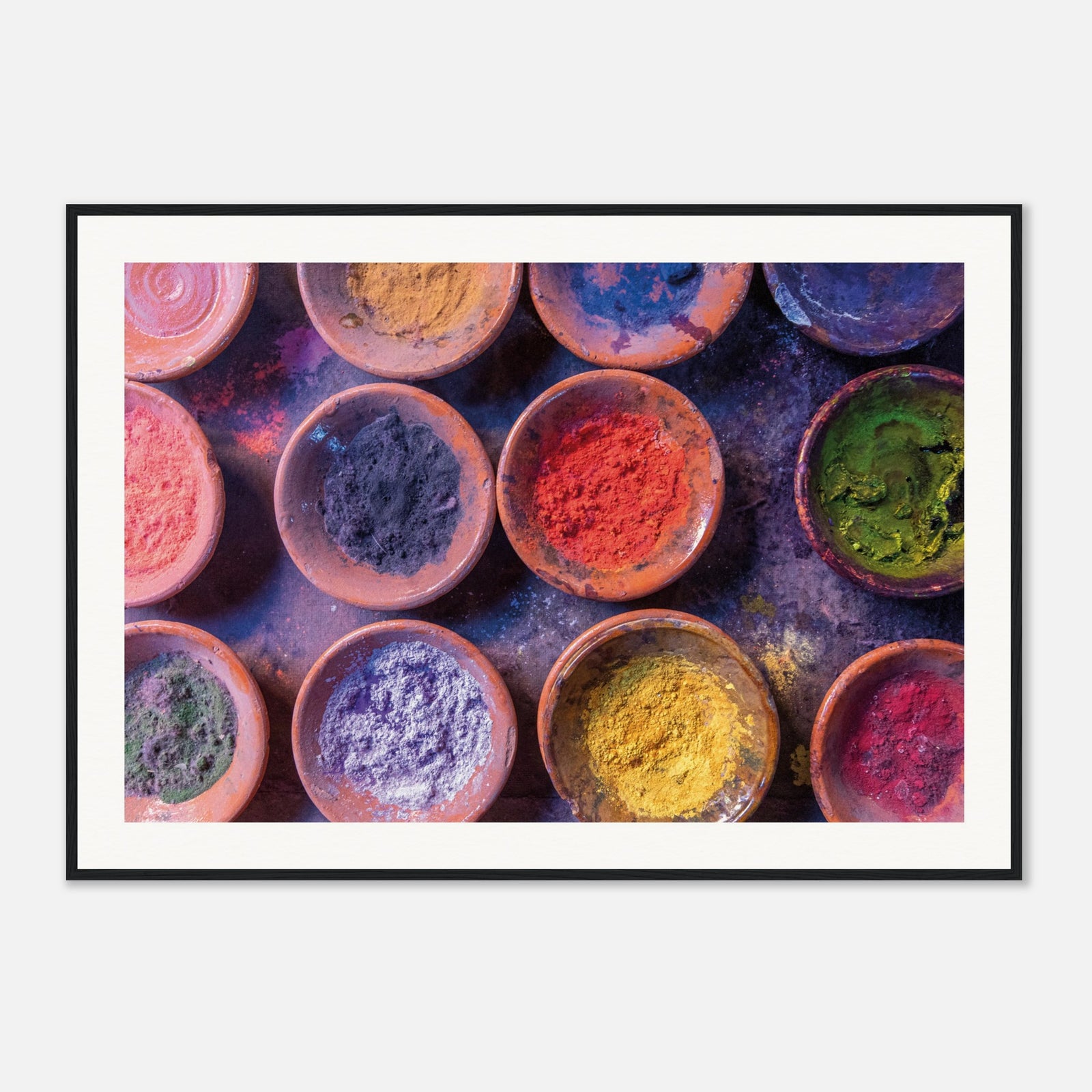 Framed top-down view of vibrant pigment bowls in earthy dishes.

