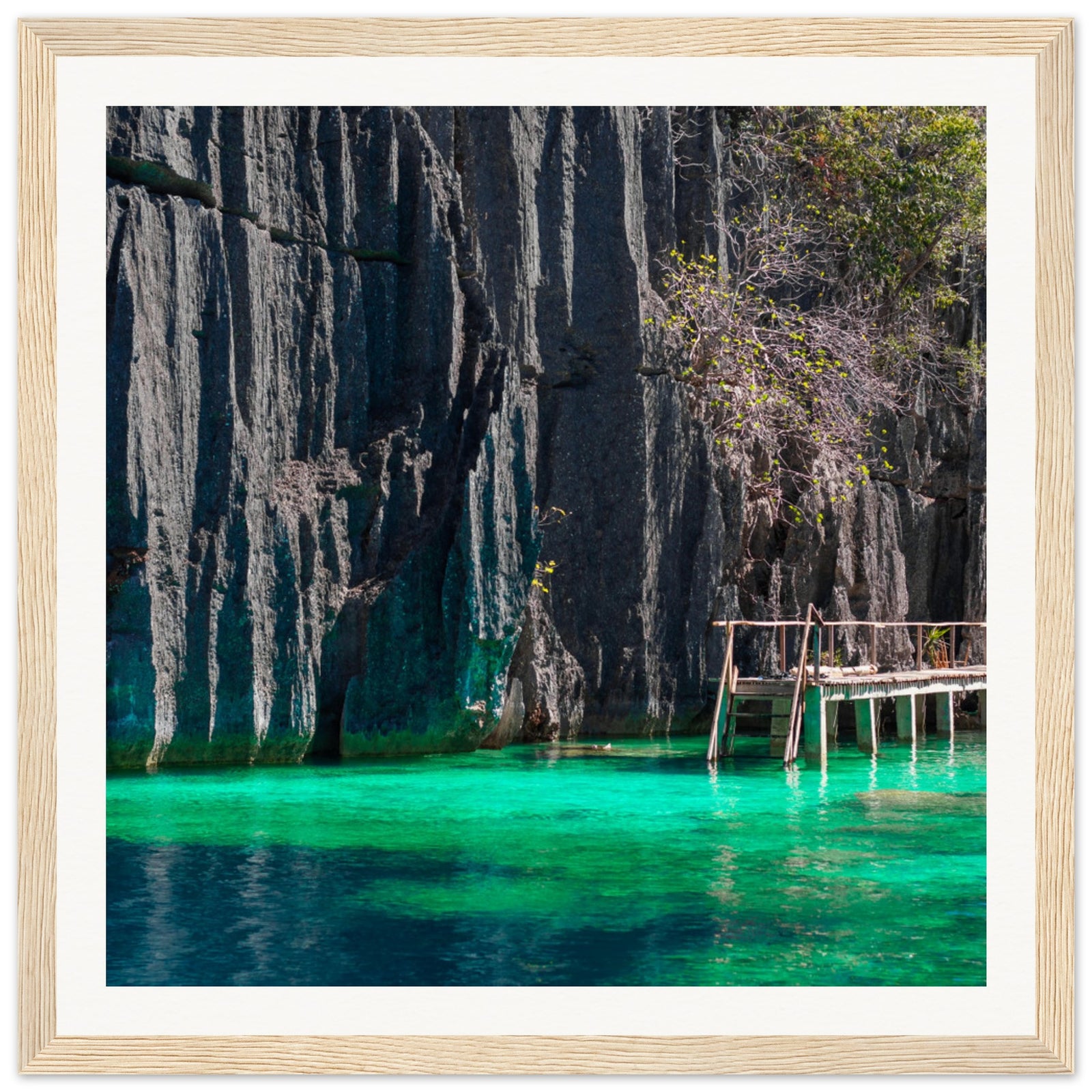 Nature portrait featuring wooden dock and turquoise waters at cliff base.

