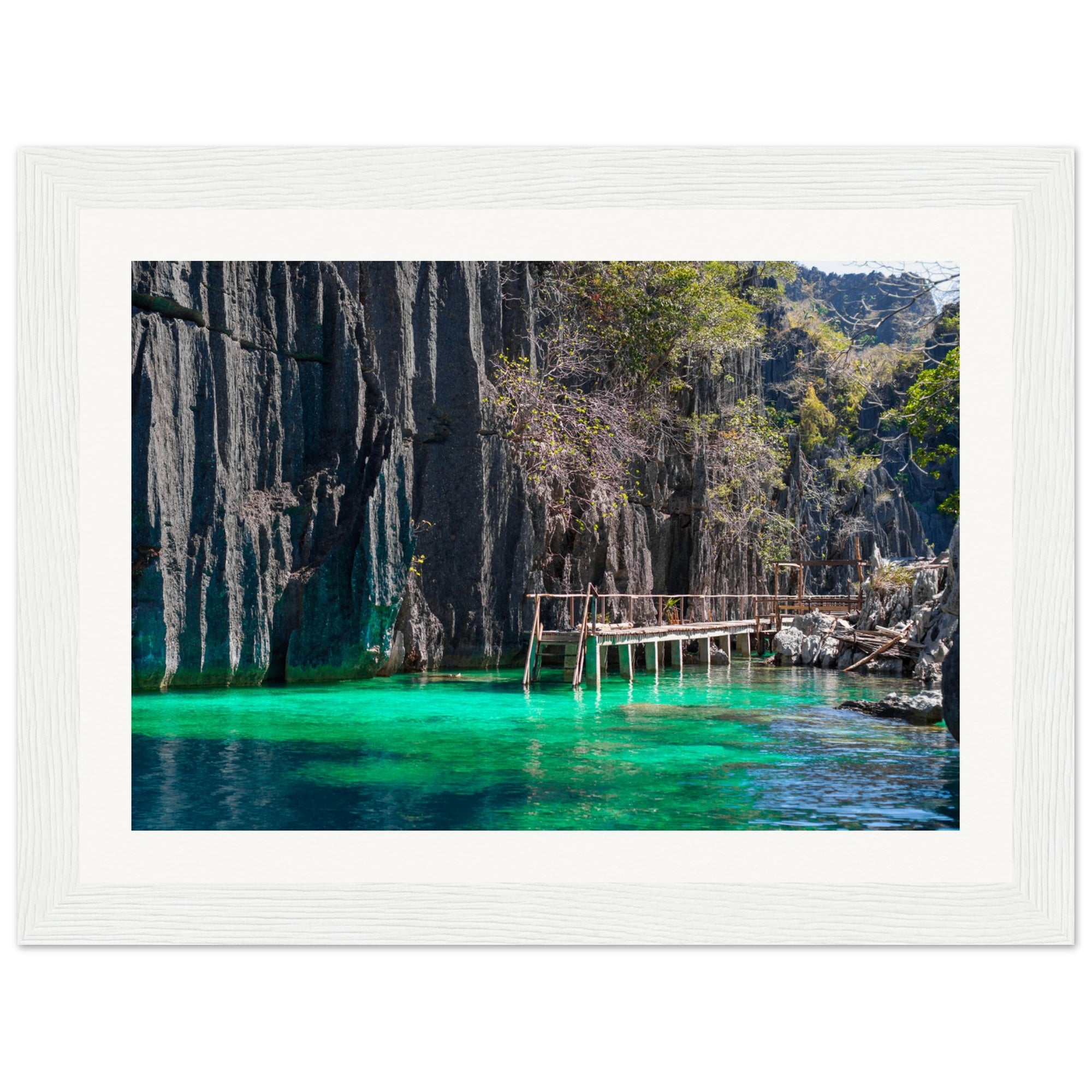 Bright emerald lagoon surrounded by dramatic cliffs in a framed photo.

