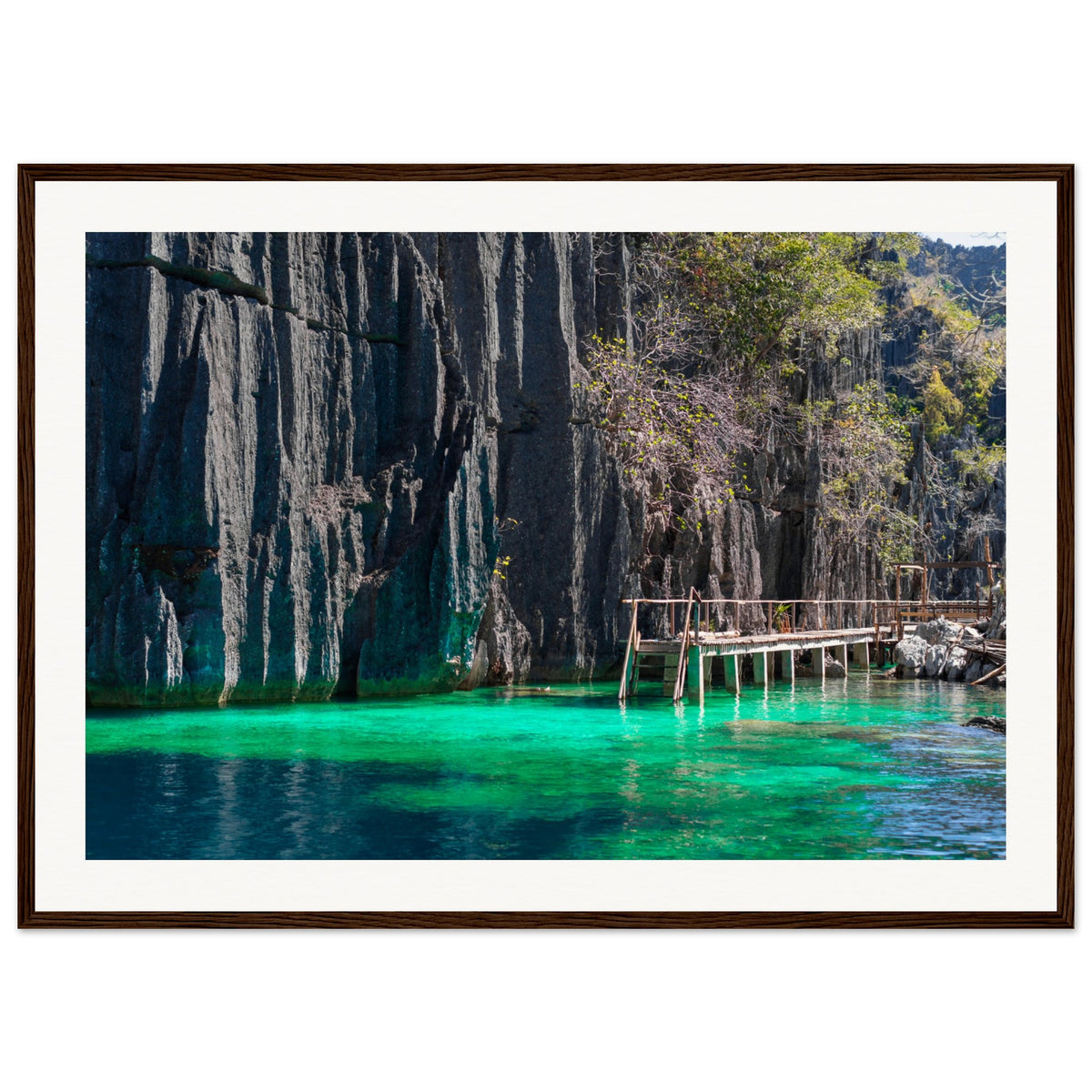 Framed coastal image of turquoise waters meeting vertical stone cliffs.

