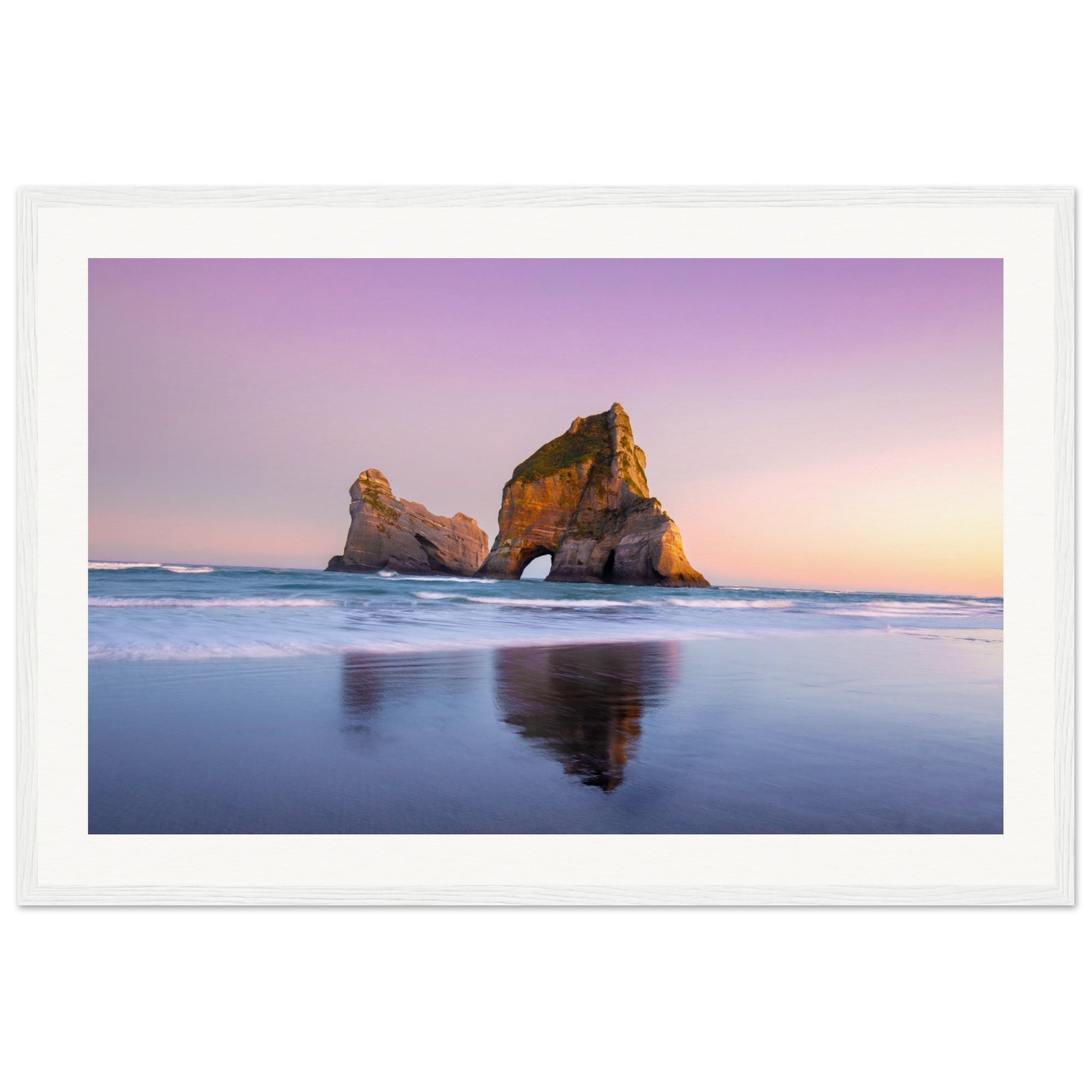 Sea rock reflected in wet sand at sunset in a framed print.


