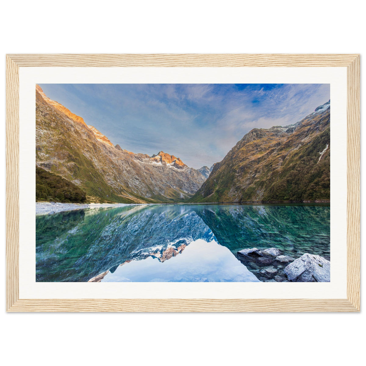 Framed portrait of a calm lake with mountains and a blue dot accent.

