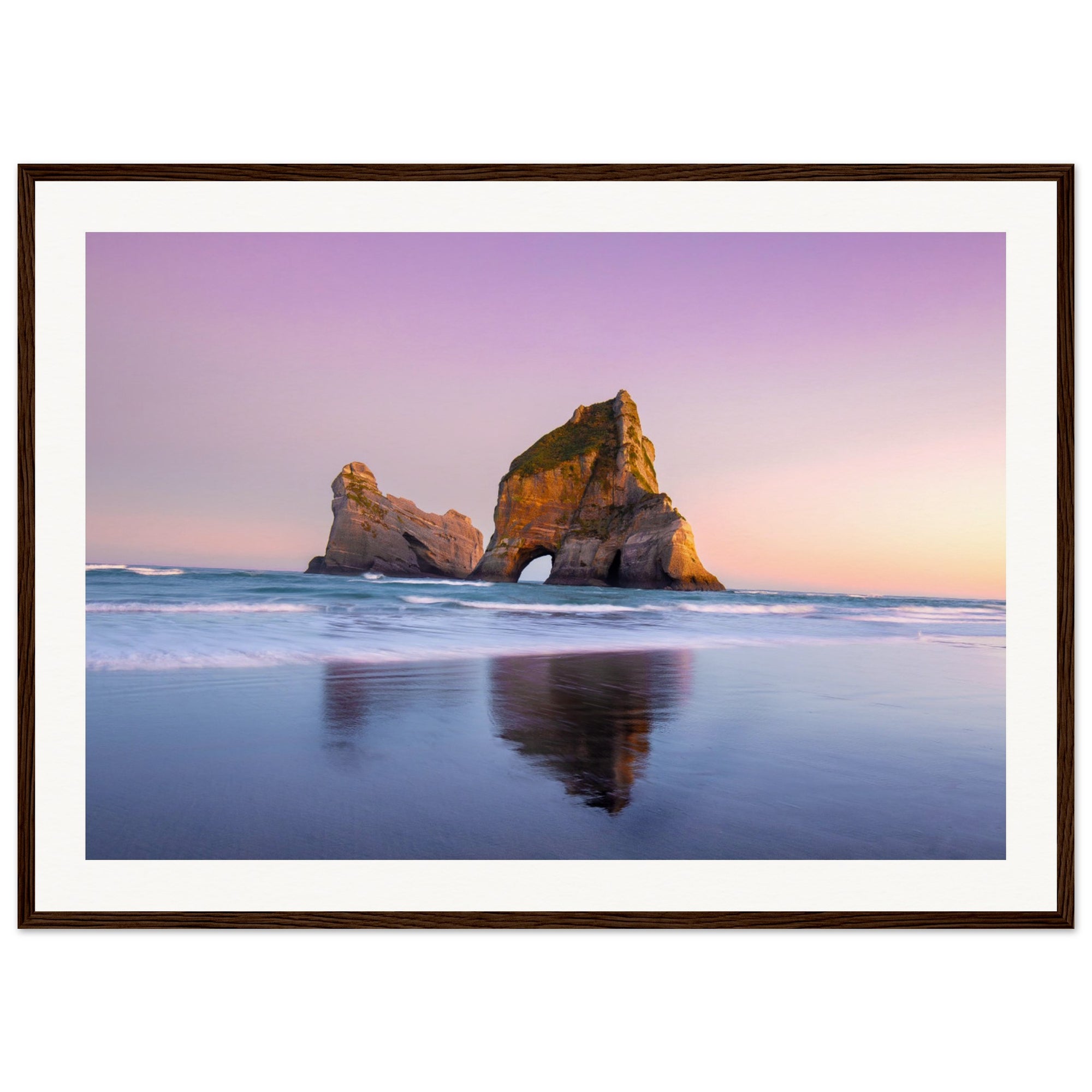 Soothing beach scene with rock formation in pastel sky.

