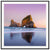Framed portrait of coastal rock arch at sunset with ocean reflection.

