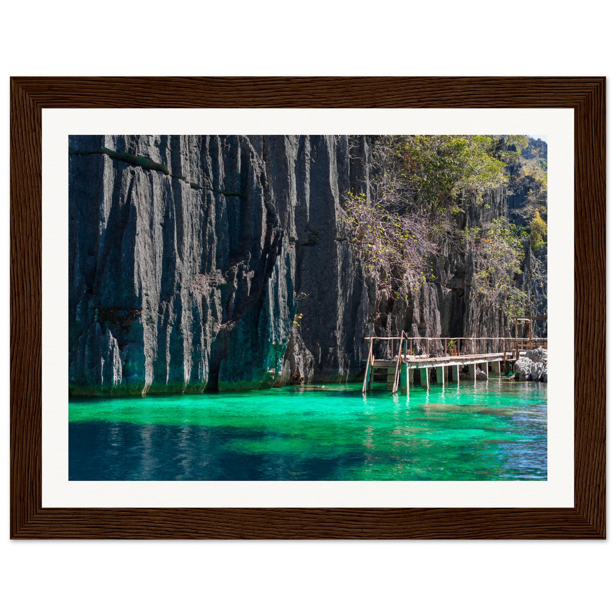 Framed nature portrait of clear turquoise water and rugged cliff face.


