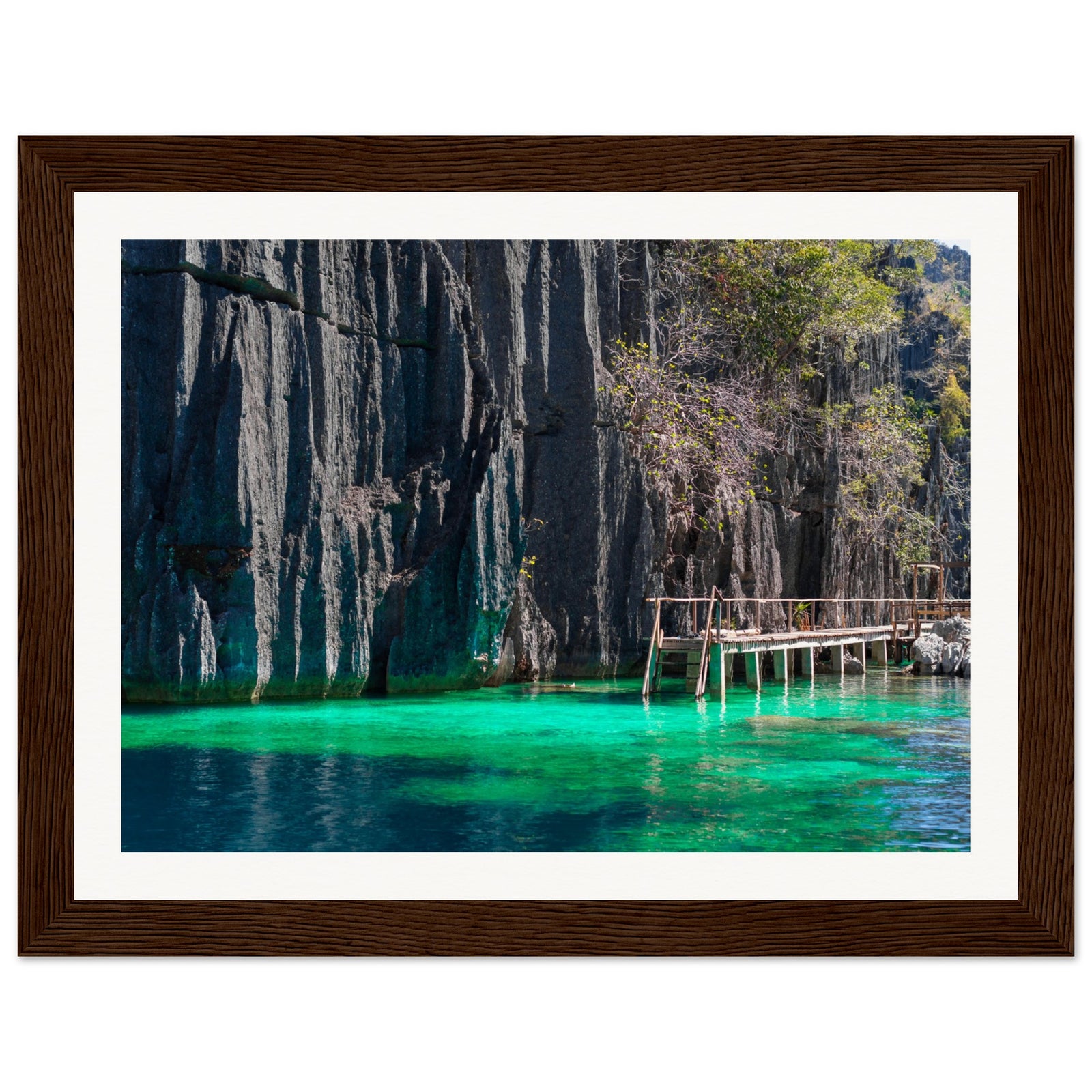Framed nature portrait of clear turquoise water and rugged cliff face.

