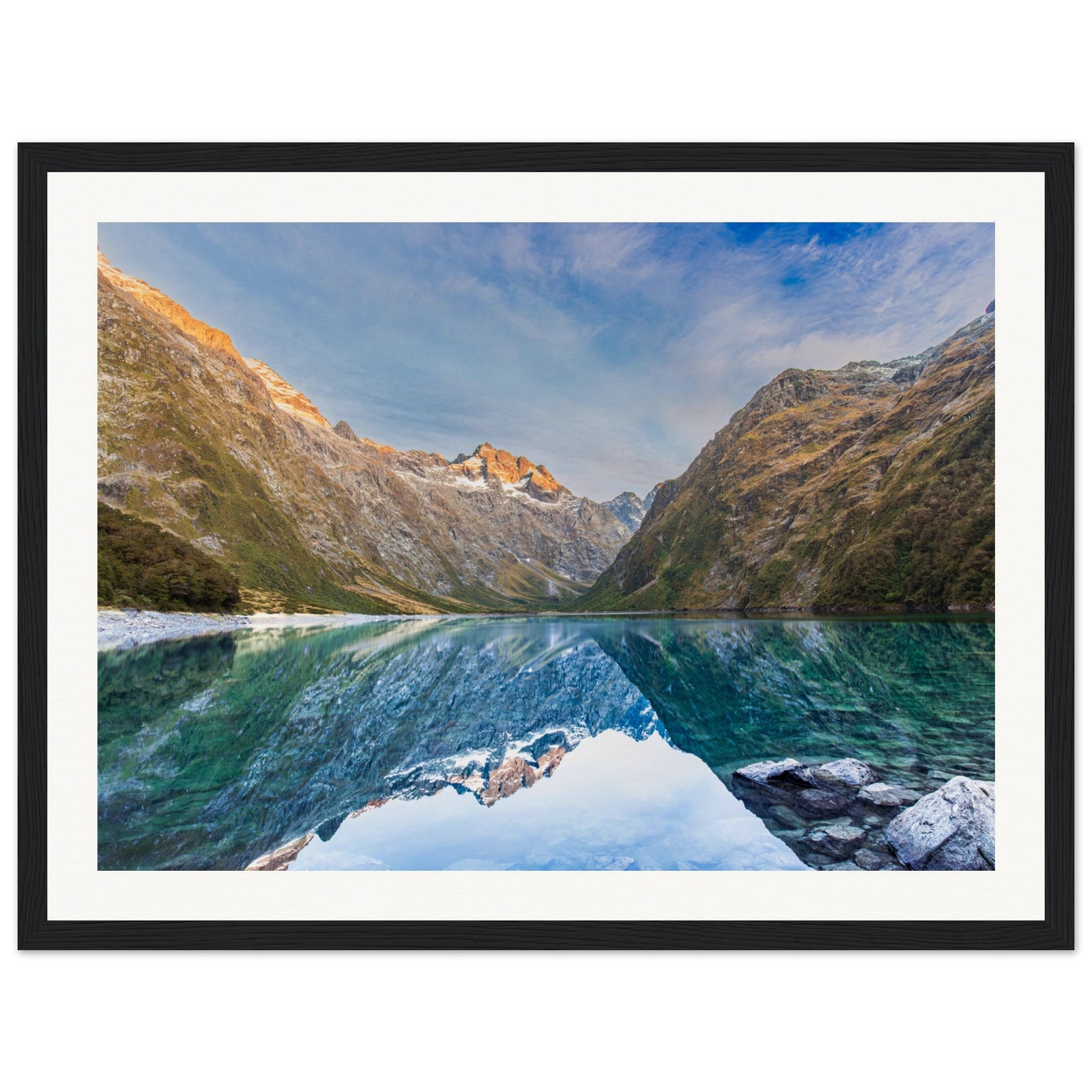 Framed nature portrait featuring a clear lake and sunlit slope.