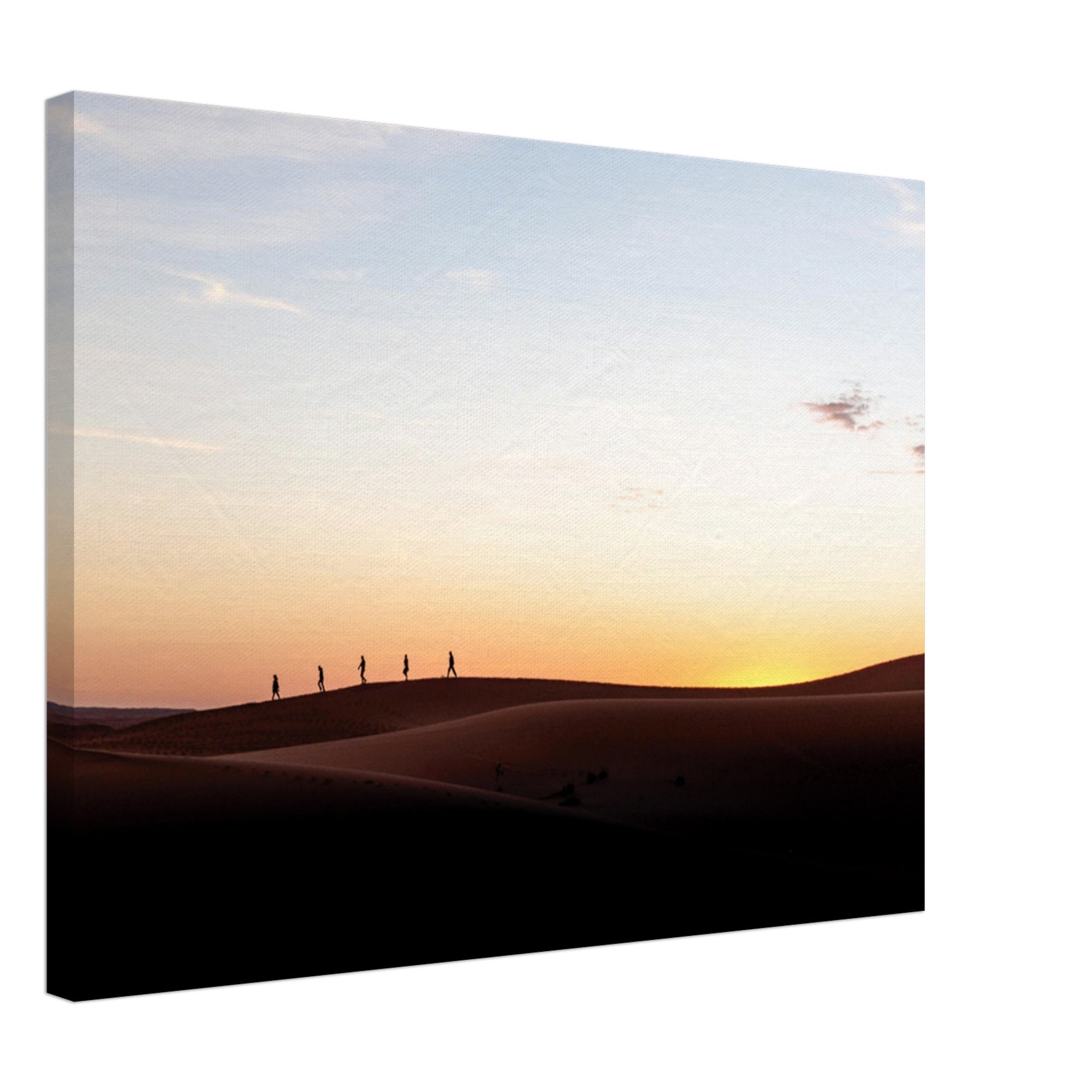 Five people hiking at sunset on vast sand dunes.

