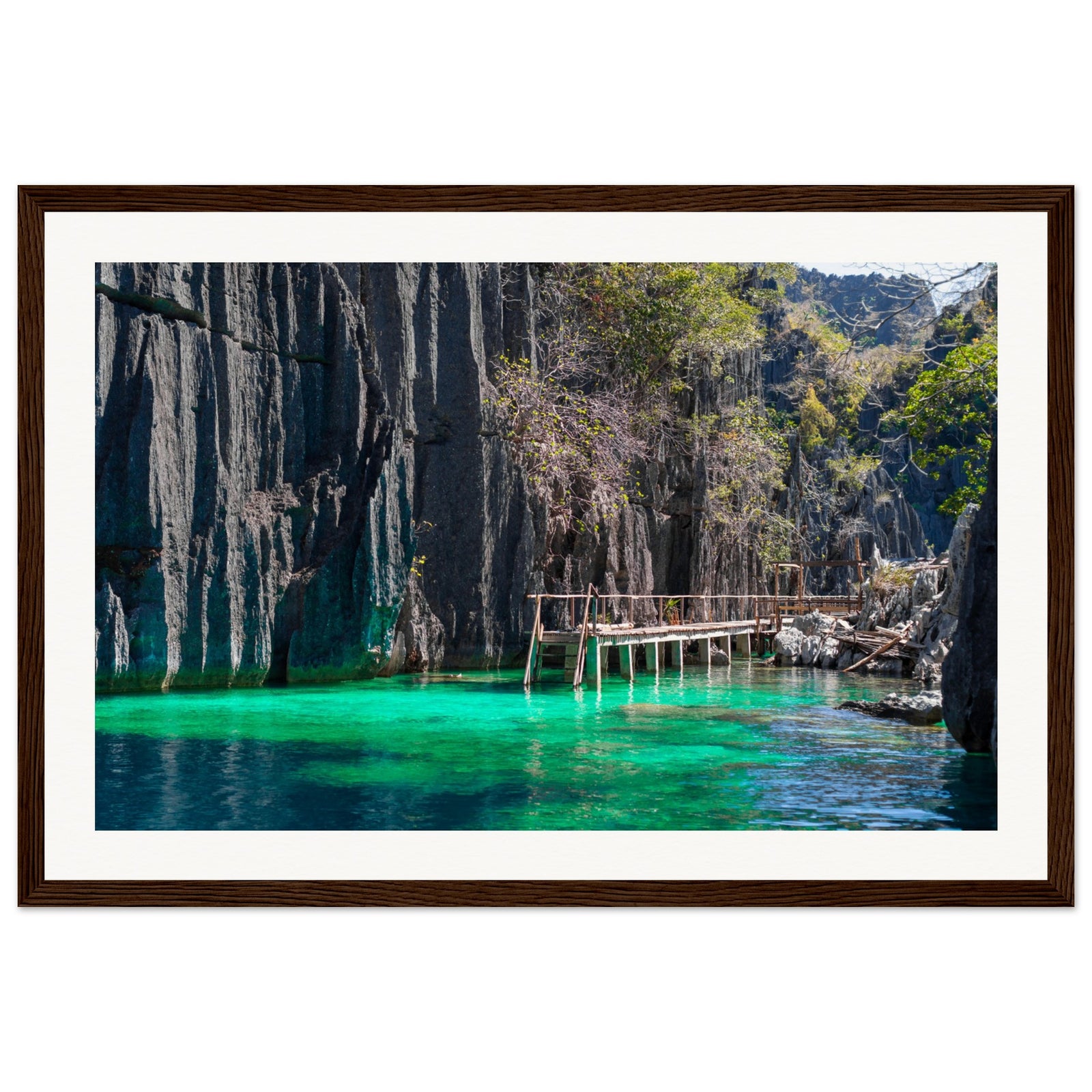 Emerald water reflecting limestone cliffs in a tropical framed portrait.

