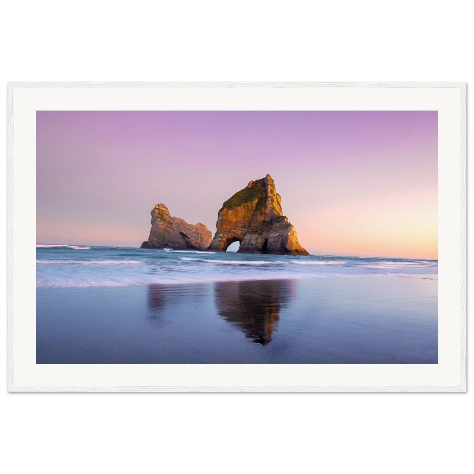 Framed image of calm ocean and iconic rock structure at sunset.

