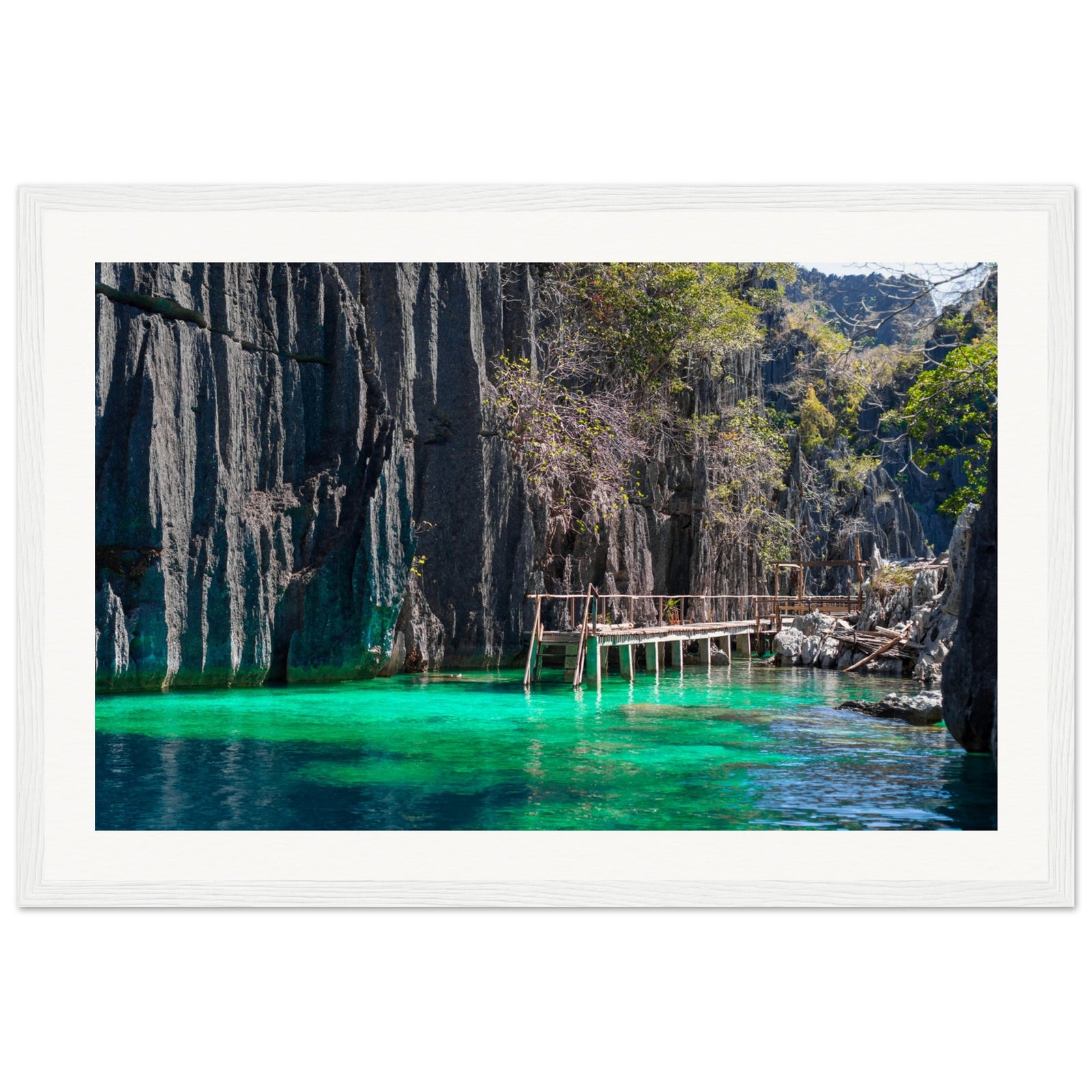 Framed coastal artwork of cliff shadows over glowing green water.


