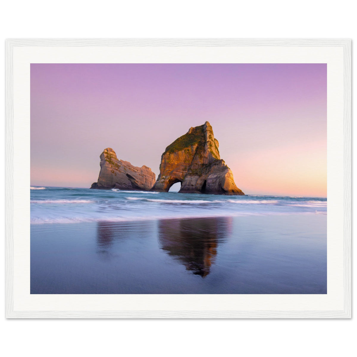 Sunset over ocean rock arch captured in a vertical portrait.

