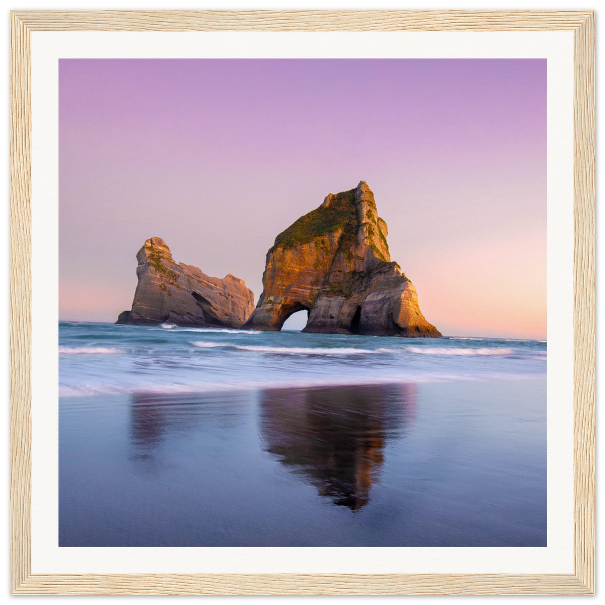 Vertical sunset seascape with natural arch and pastel sky hues.

