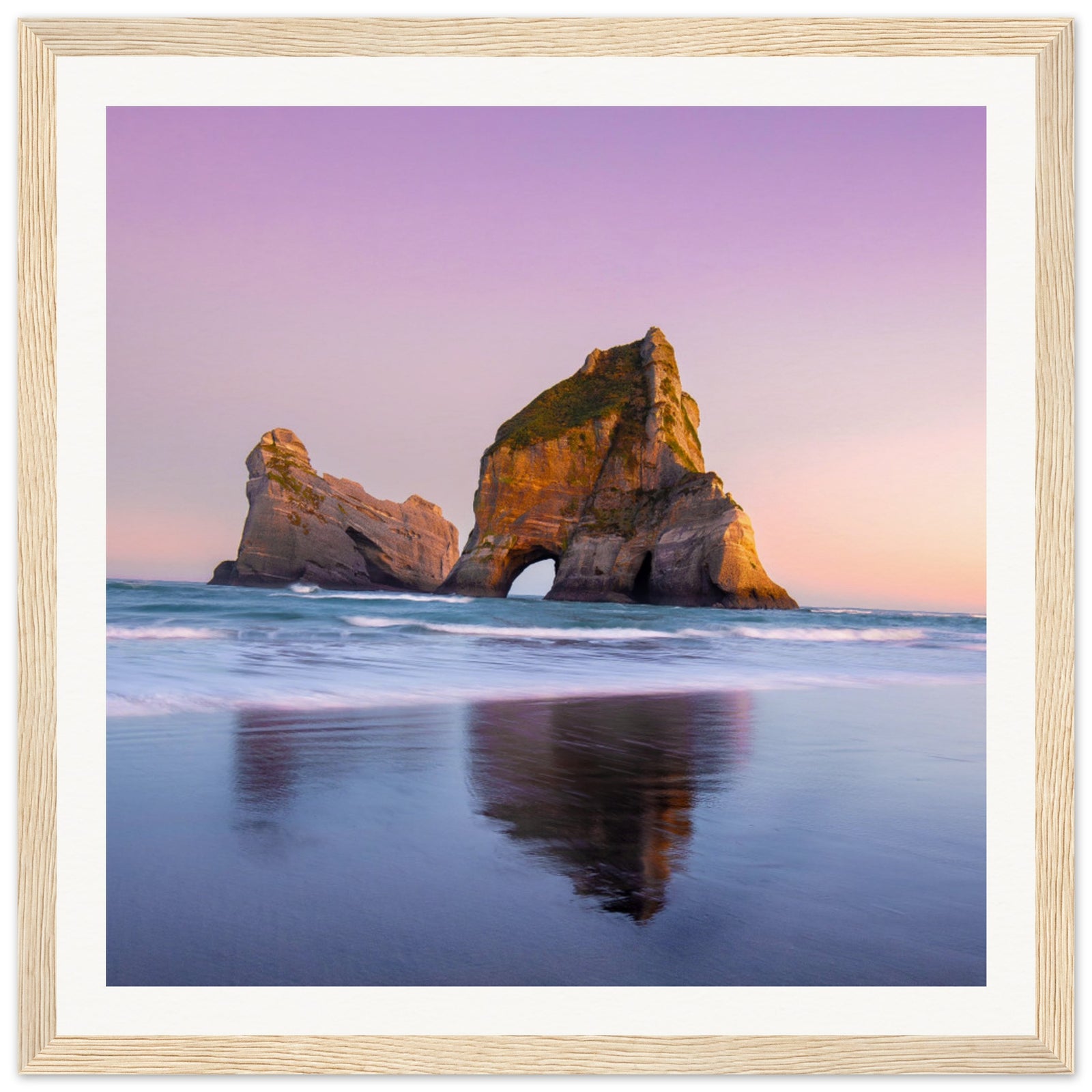 Vertical sunset seascape with natural arch and pastel sky hues.

