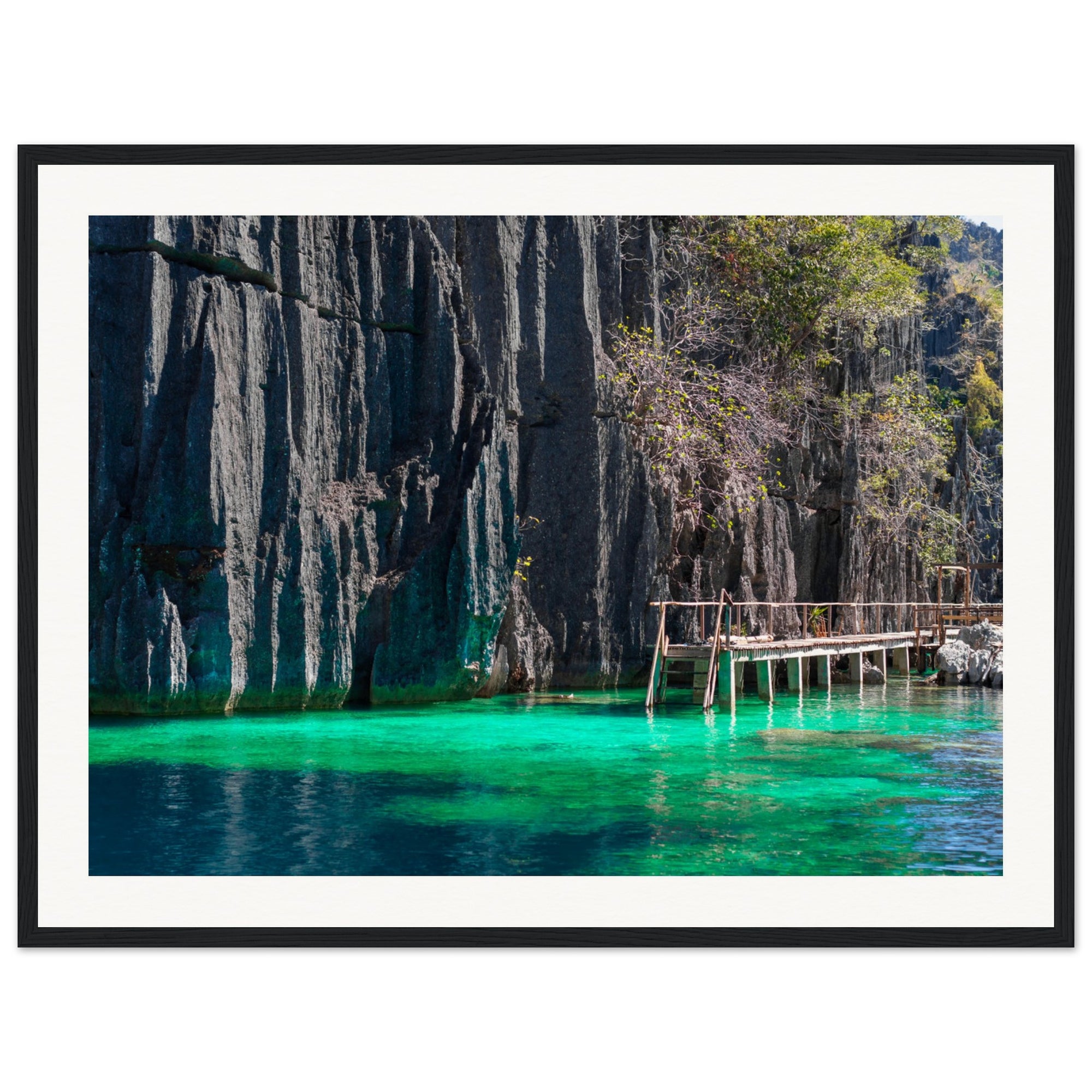 Tropical water scene with limestone cliffs and wooden walkway in a frame.

