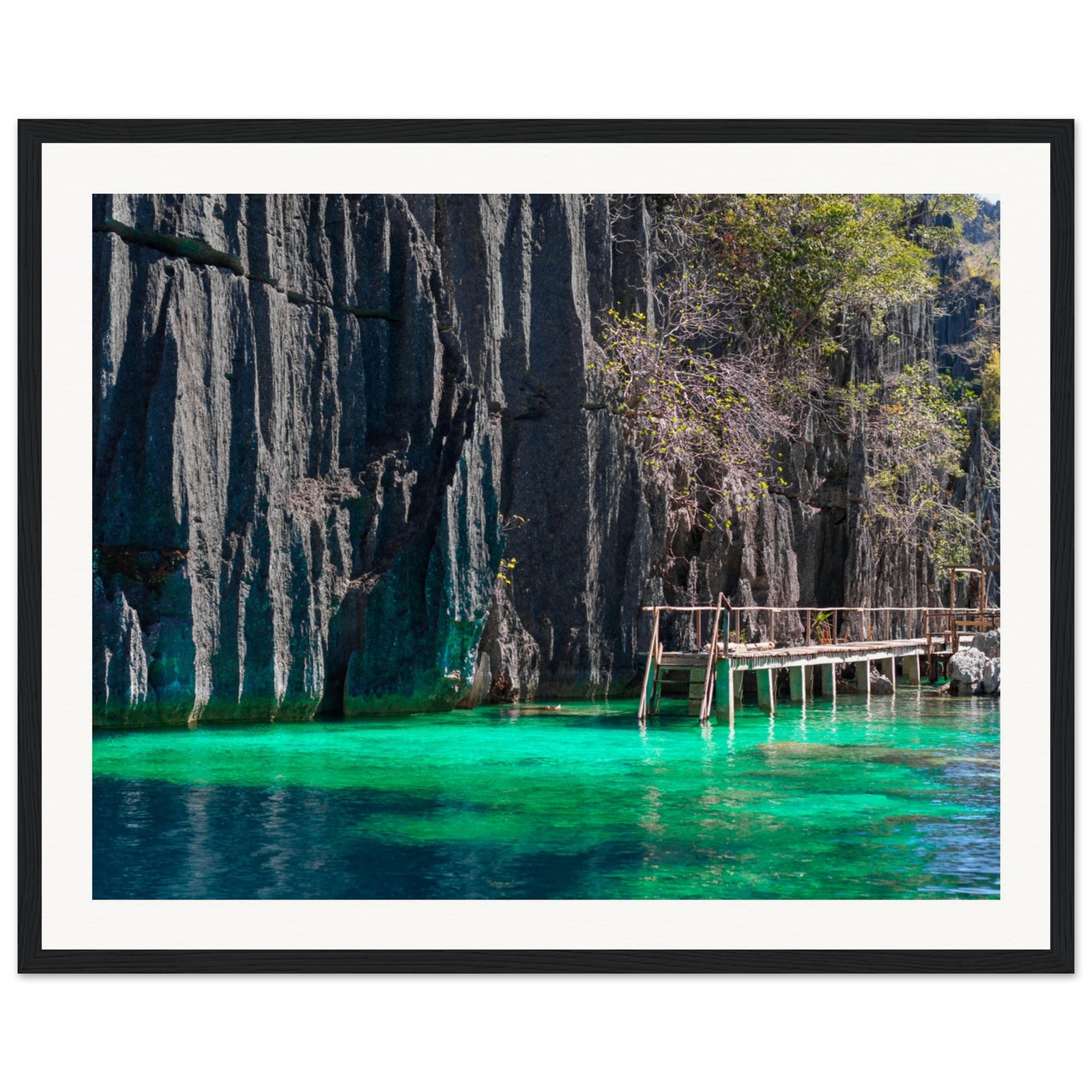 Rustic boardwalk beside limestone cliffs and vibrant tropical waters.

