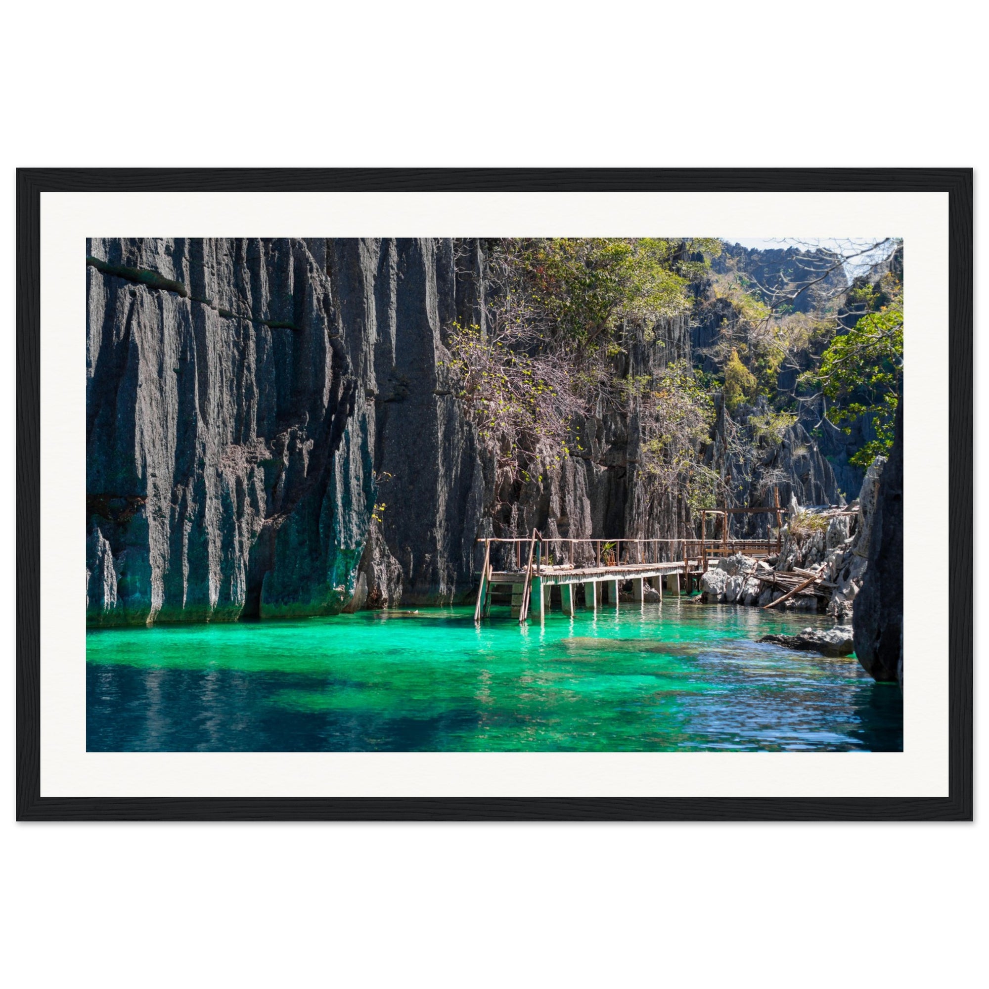 Tranquil green lagoon with rocky cliffs and a rustic dock in wall art.

