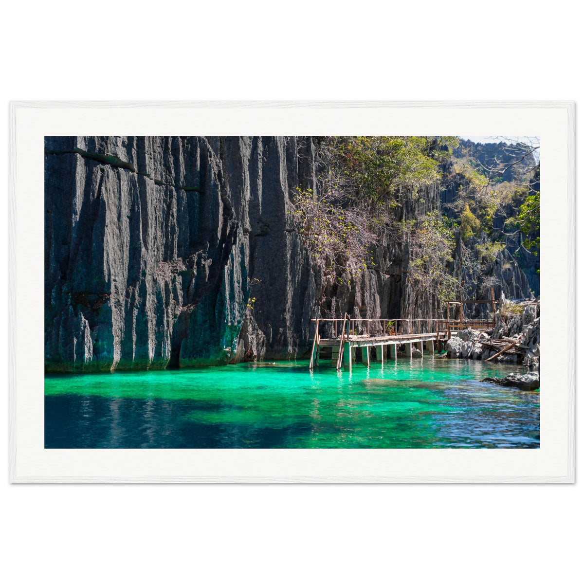 Framed scene of tropical water, vertical cliffs, and trees.

