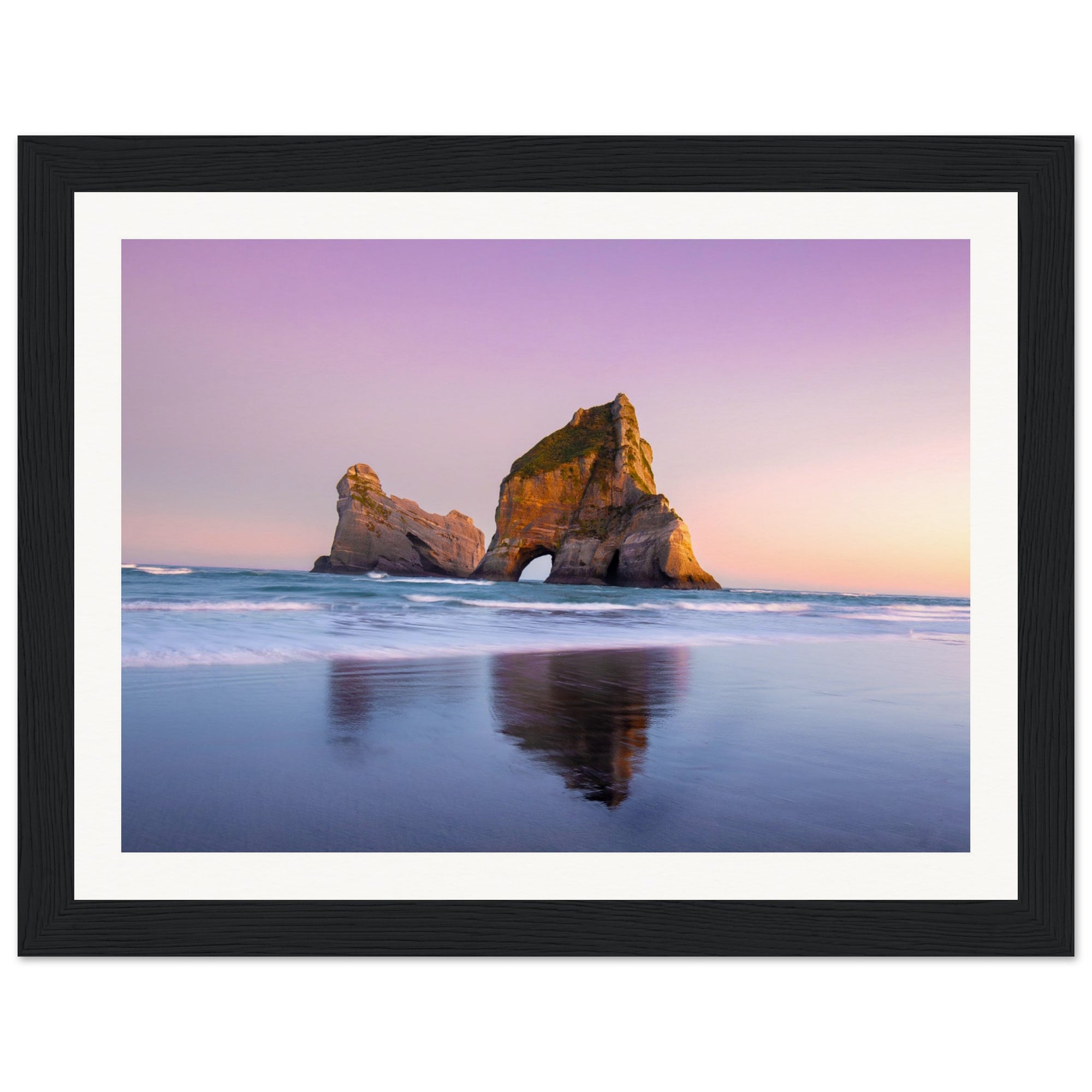 Framed vertical view of beach at dusk with rocky outcrop.

