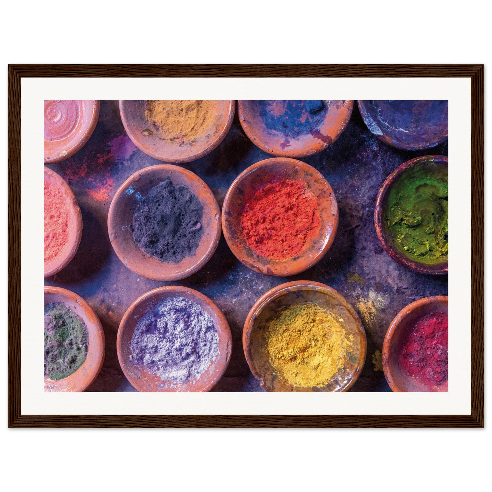 Colorful Holi powders set in earthy bowls as a framed artwork.

