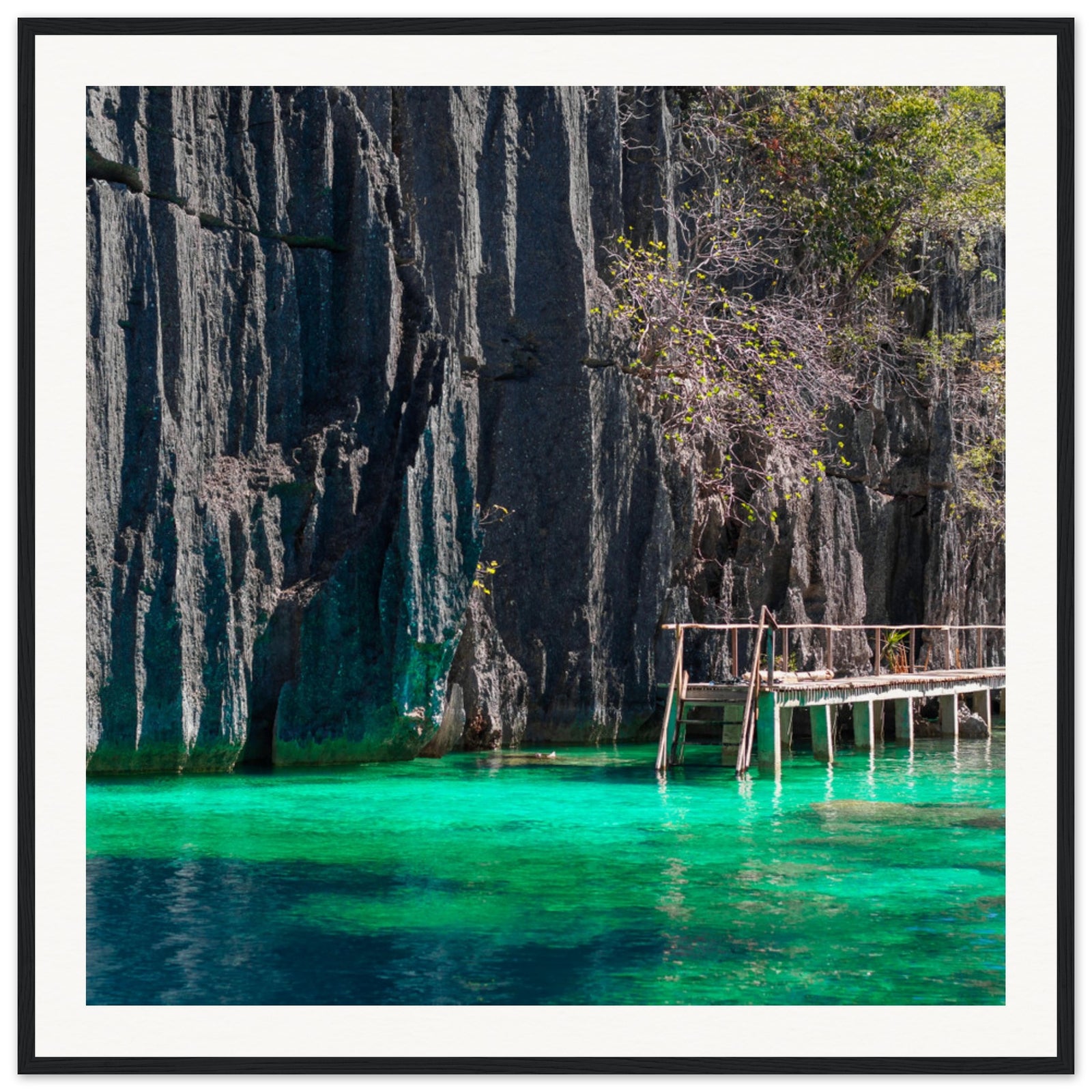 Jagged rock walls over turquoise waters in a tranquil framed print.

