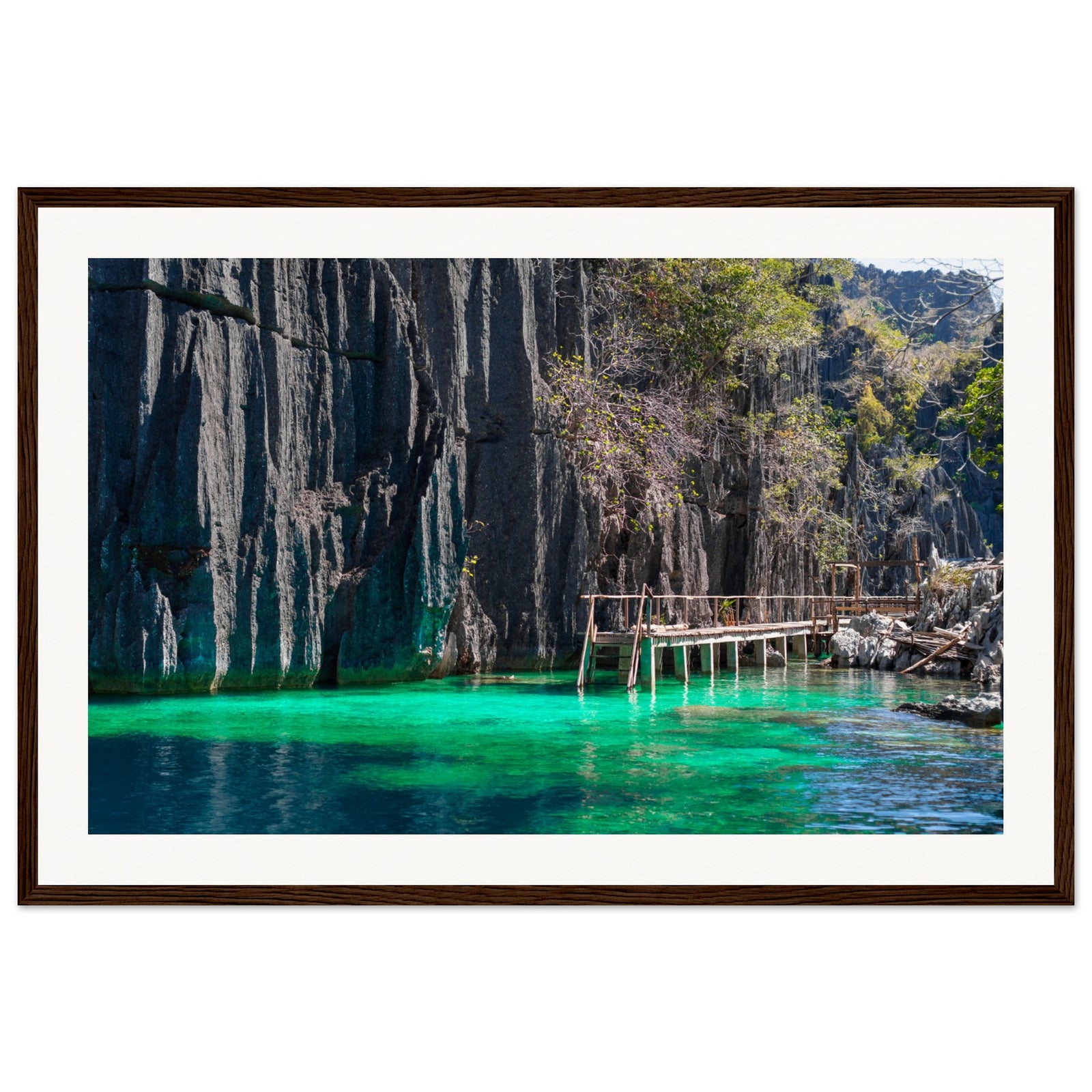 Peaceful lagoon with stilted walkway and steep cliffs in a portrait view.

