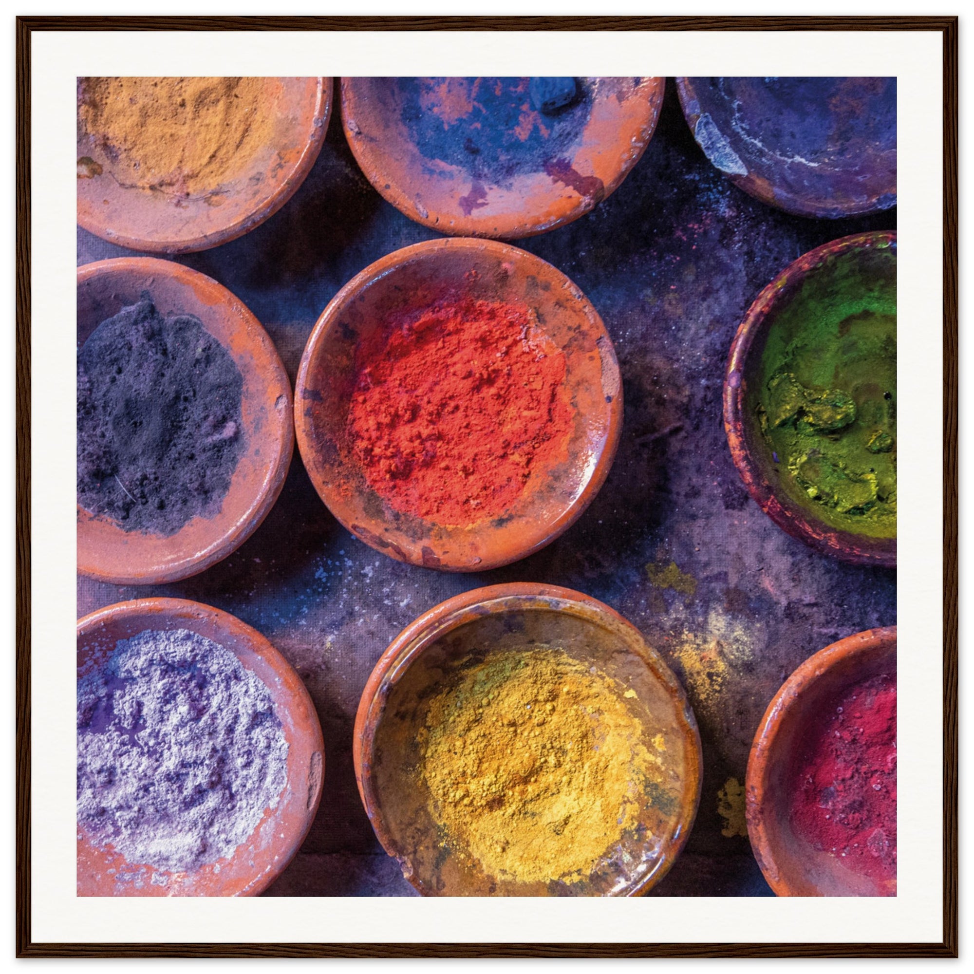 Bright festival pigments in terracotta dishes for wall display.

