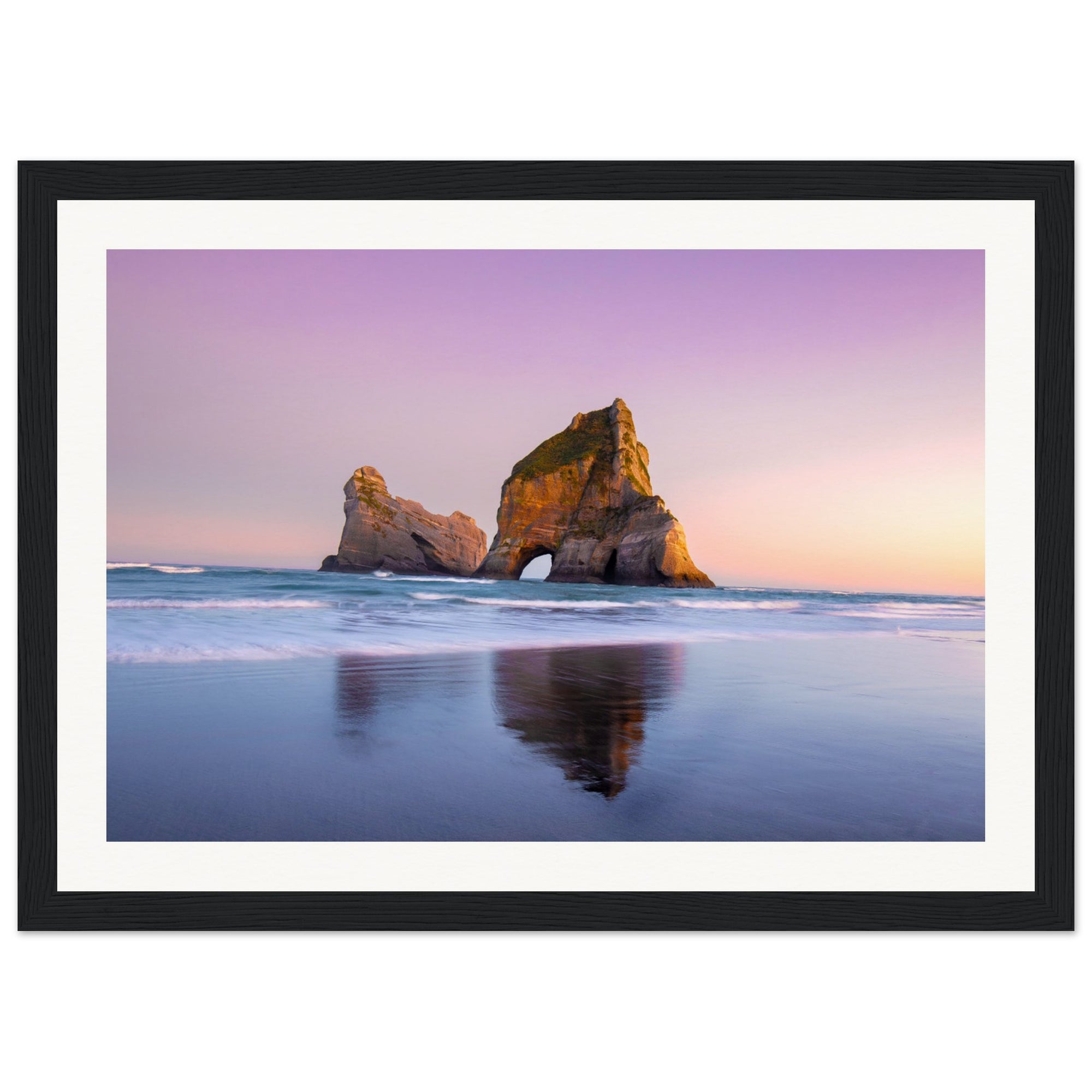 Framed scenic view of rock structure rising from ocean at twilight.

