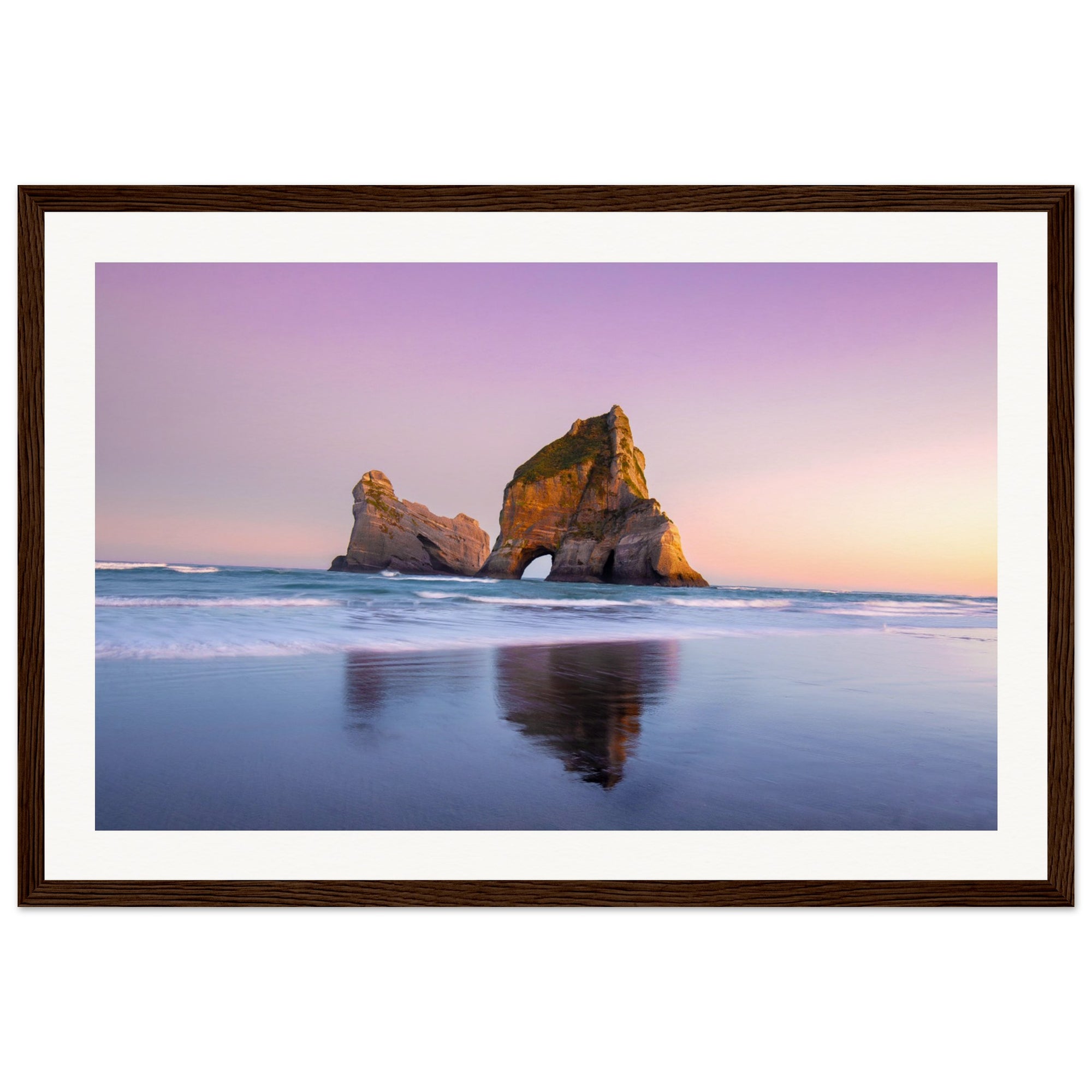 Coastal landscape portrait with natural rock arch and still waves.

