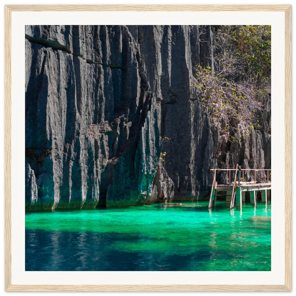 Wooden dock stretching over clear water below limestone cliffs.

