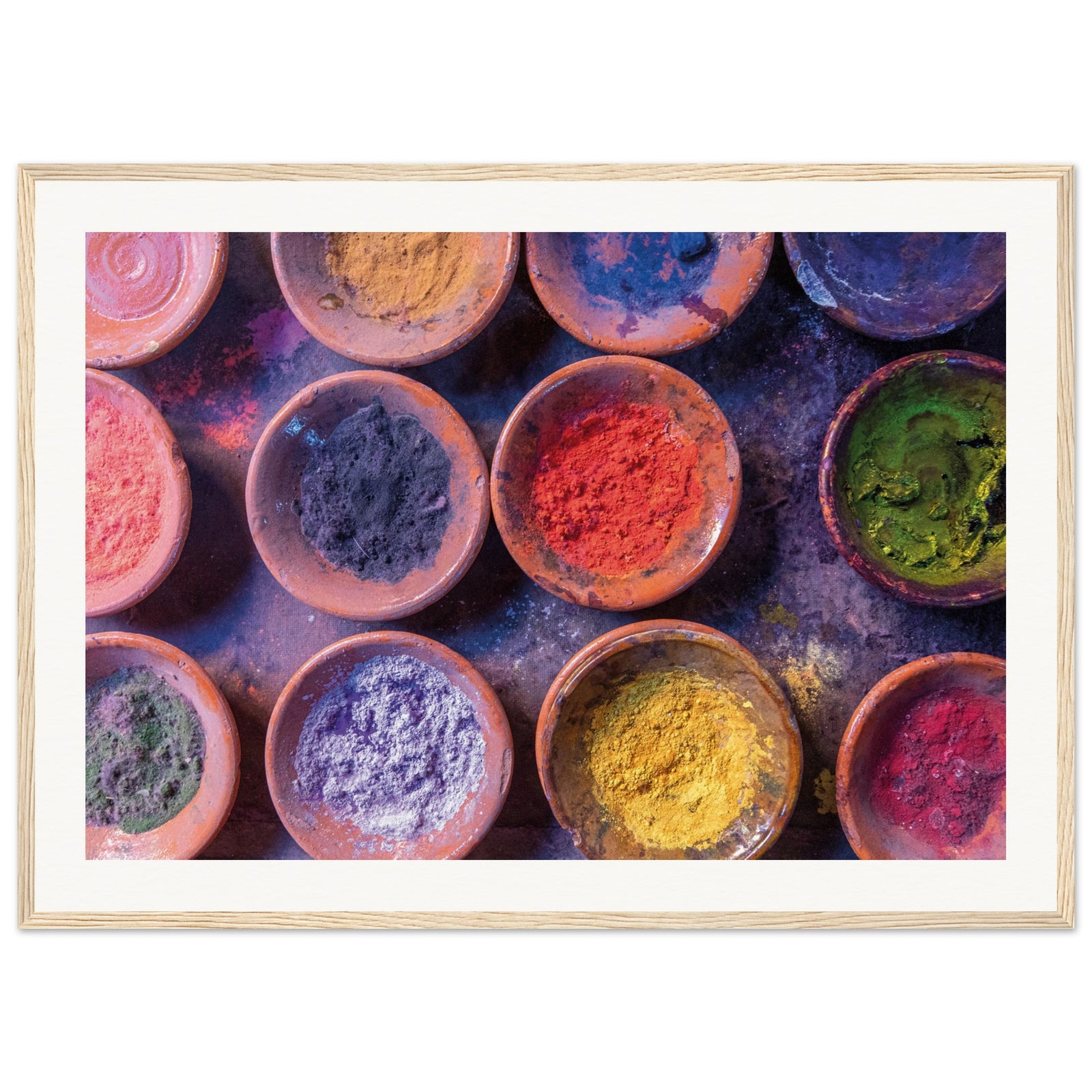 Brightly colored natural dyes in terracotta bowls displayed in a print.

