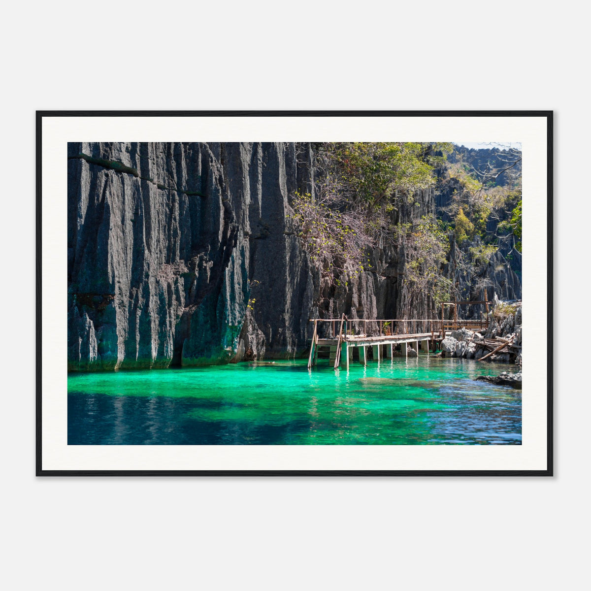 Framed photo of emerald water and limestone cliffs with a wooden walkway.

